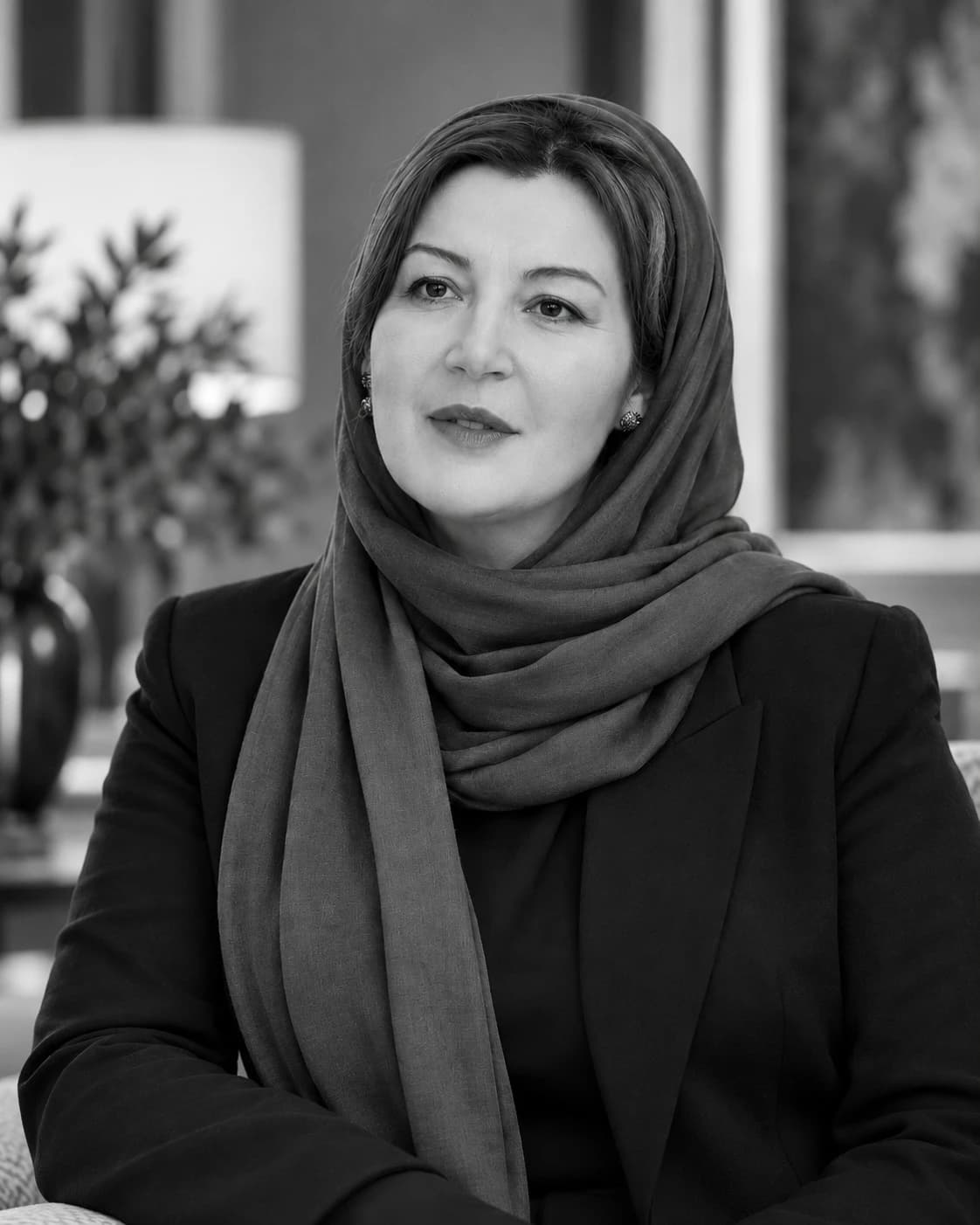 Retrato de Jihane Alhalabi em preto e branco, com lenço e blazer escuro